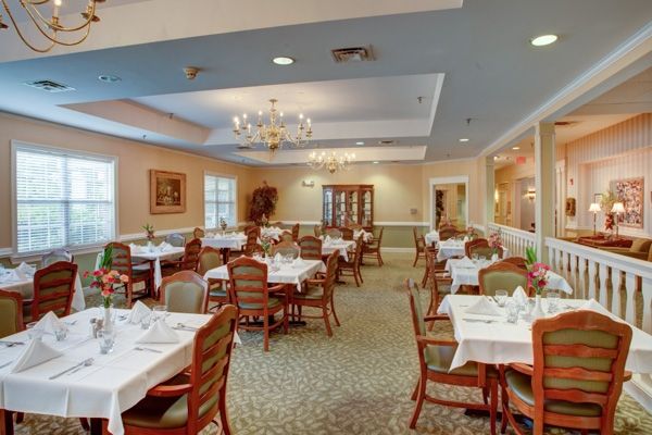 An elegant dining room with neatly arranged tables and chairs, adorned with chandeliers.