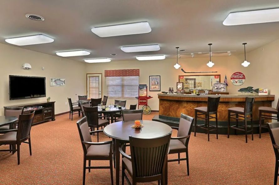 A cozy dining area with tables, chairs, and a bar counter under bright ceiling lights.