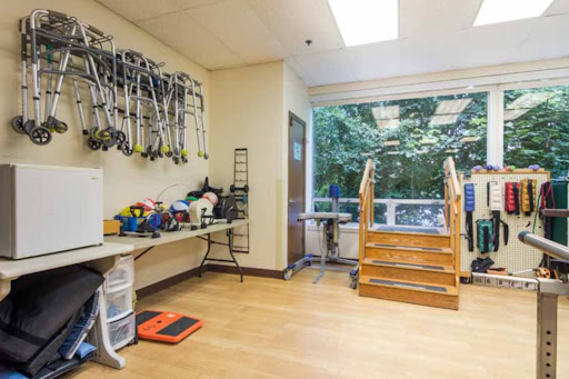 A well-lit therapy room equipped with exercise tools and stairs, designed for rehabilitation activities.