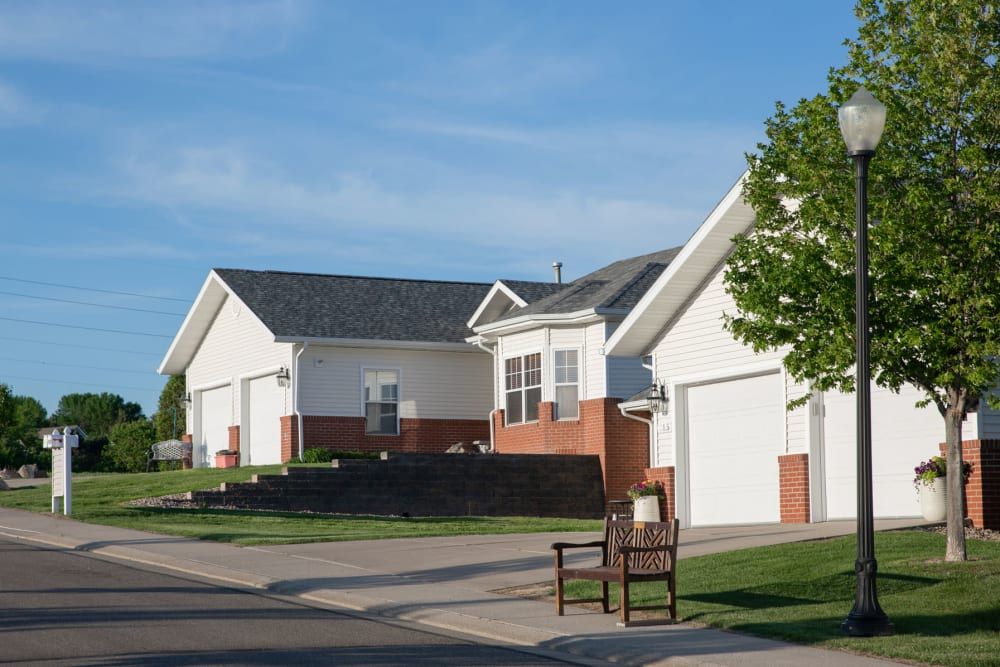 A quiet suburban street lined with modern single-story houses featuring driveways and front lawns.