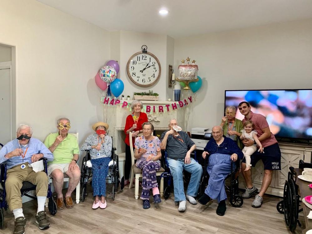 A joyful birthday celebration with a group of elderly people gathered around, featuring colorful balloons and decorations.
