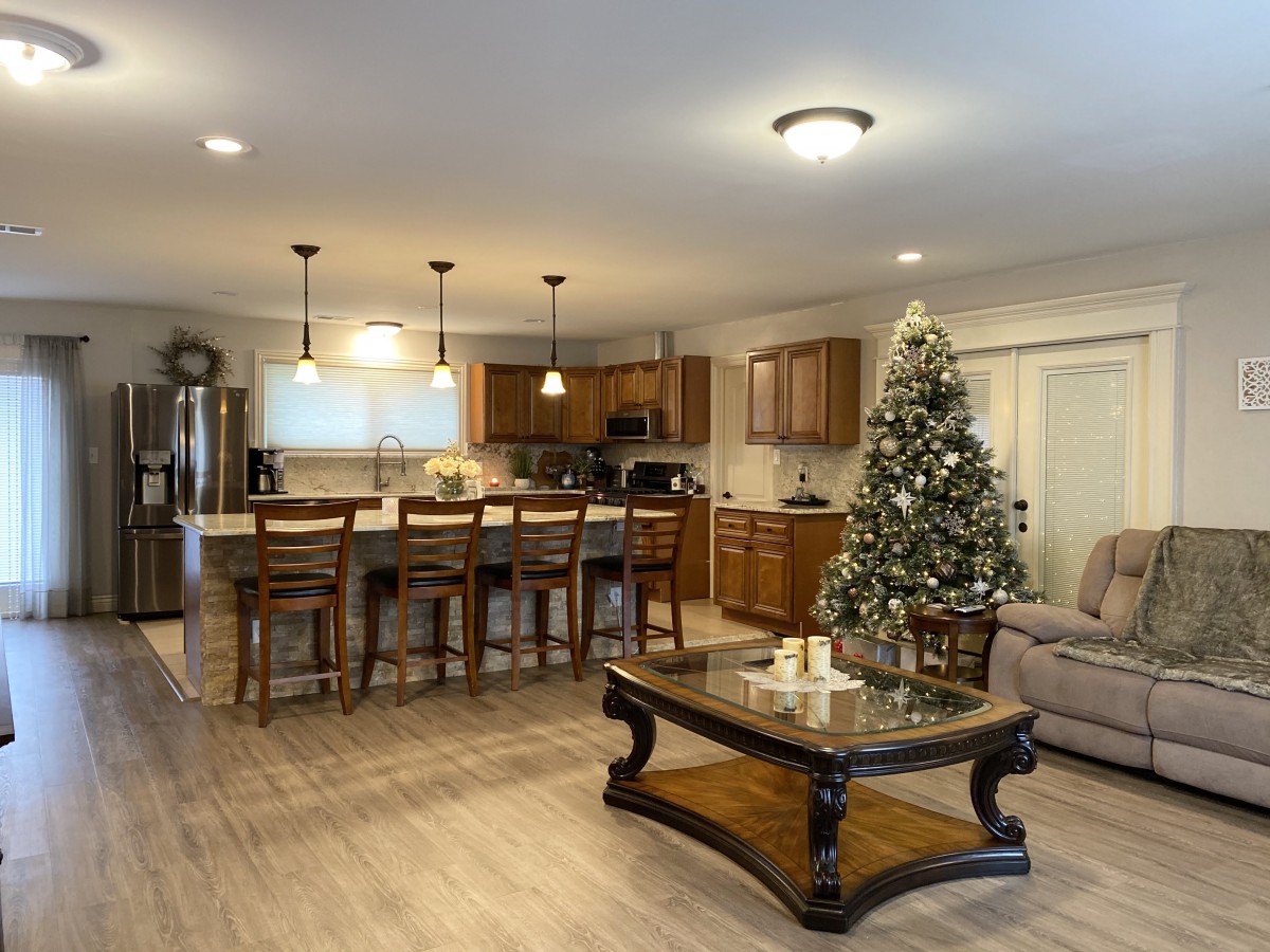 A cozy open-concept kitchen and living room featuring a decorated Christmas tree.