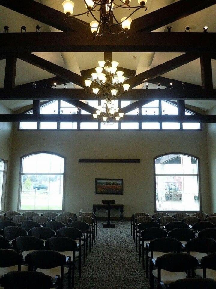 Interior view of a chapel with rows of seating and large windows allowing natural light.