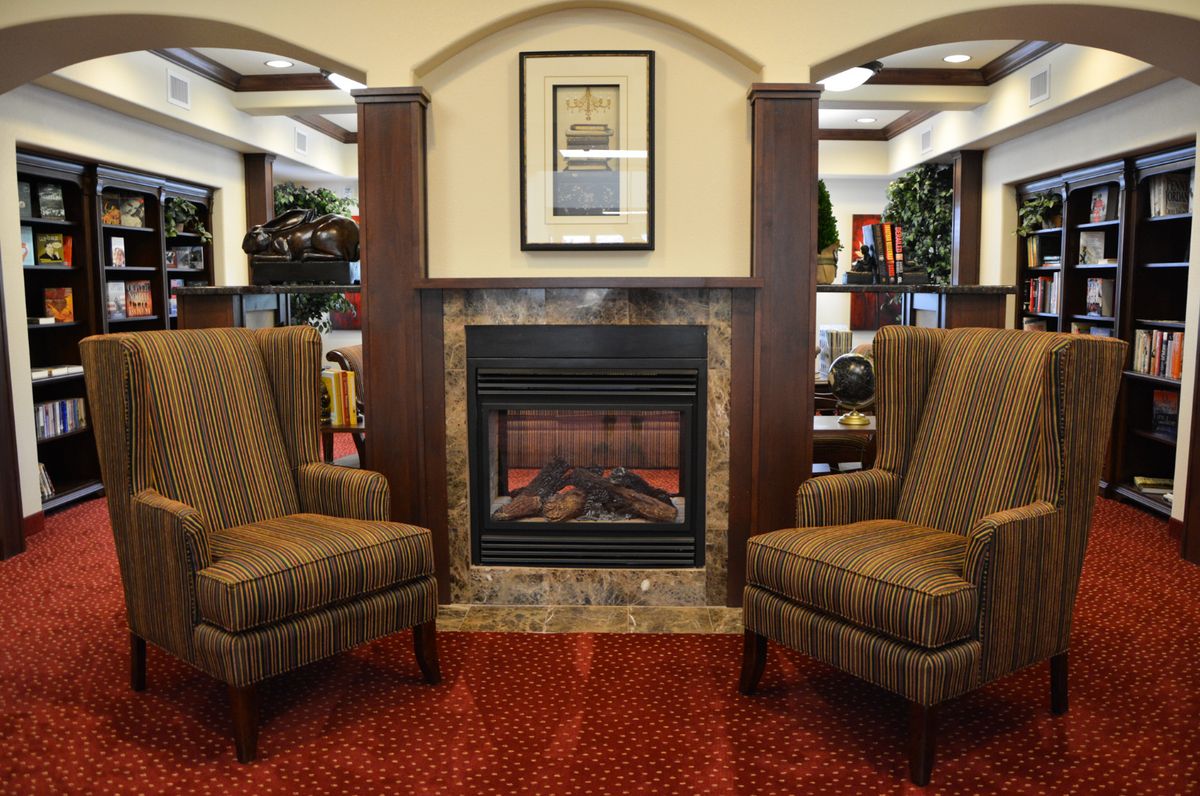 A cozy seating area with two armchairs flanking a fireplace in a warmly decorated room.