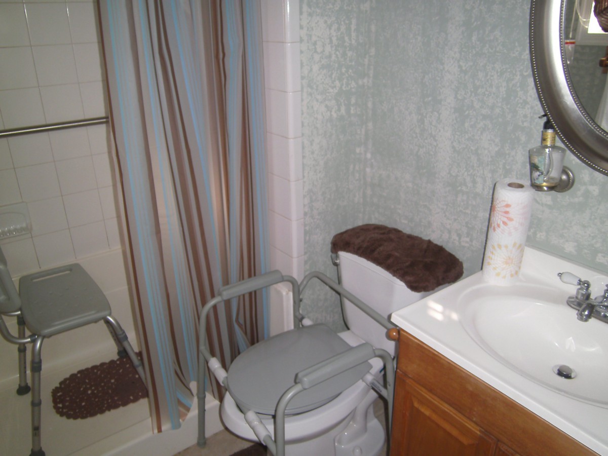 A bathroom featuring a toilet with assistive seating, a shower with a curtain, and a sink.