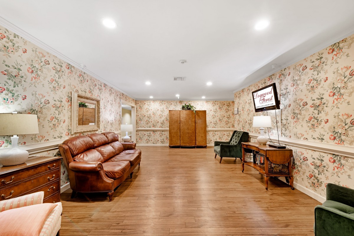 Cozy living room with wooden floors, leather sofa, armchair, and patterned wallpaper.