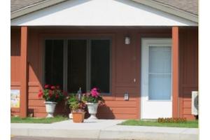 A small house with a front porch and flower pots.
