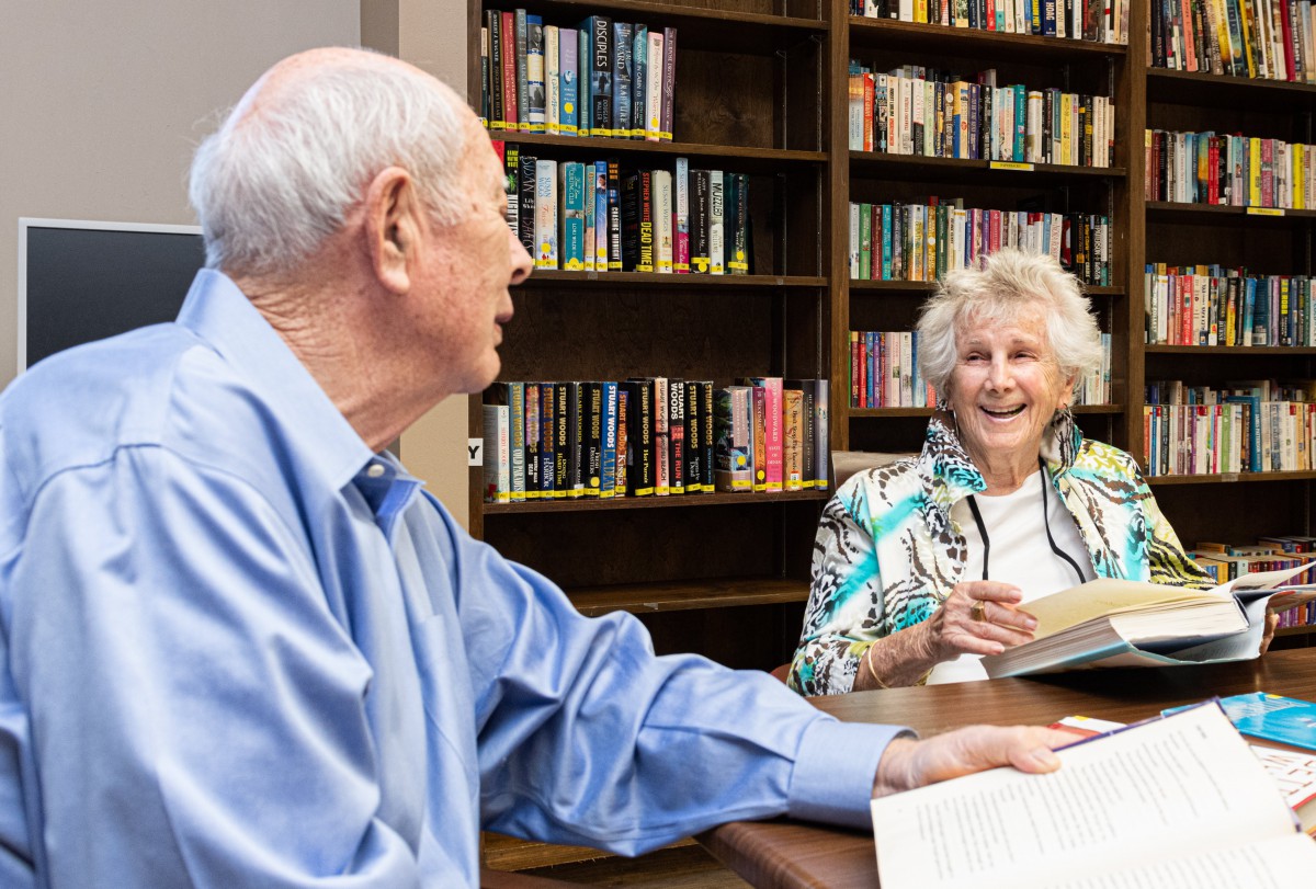 Elderly couple engaged in a lively discussion at the library.