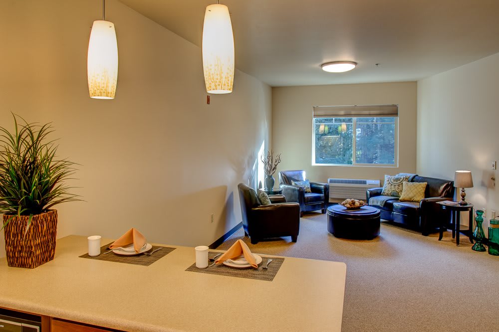 A modern living space featuring a cozy seating area and a small dining table under stylish pendant lights.