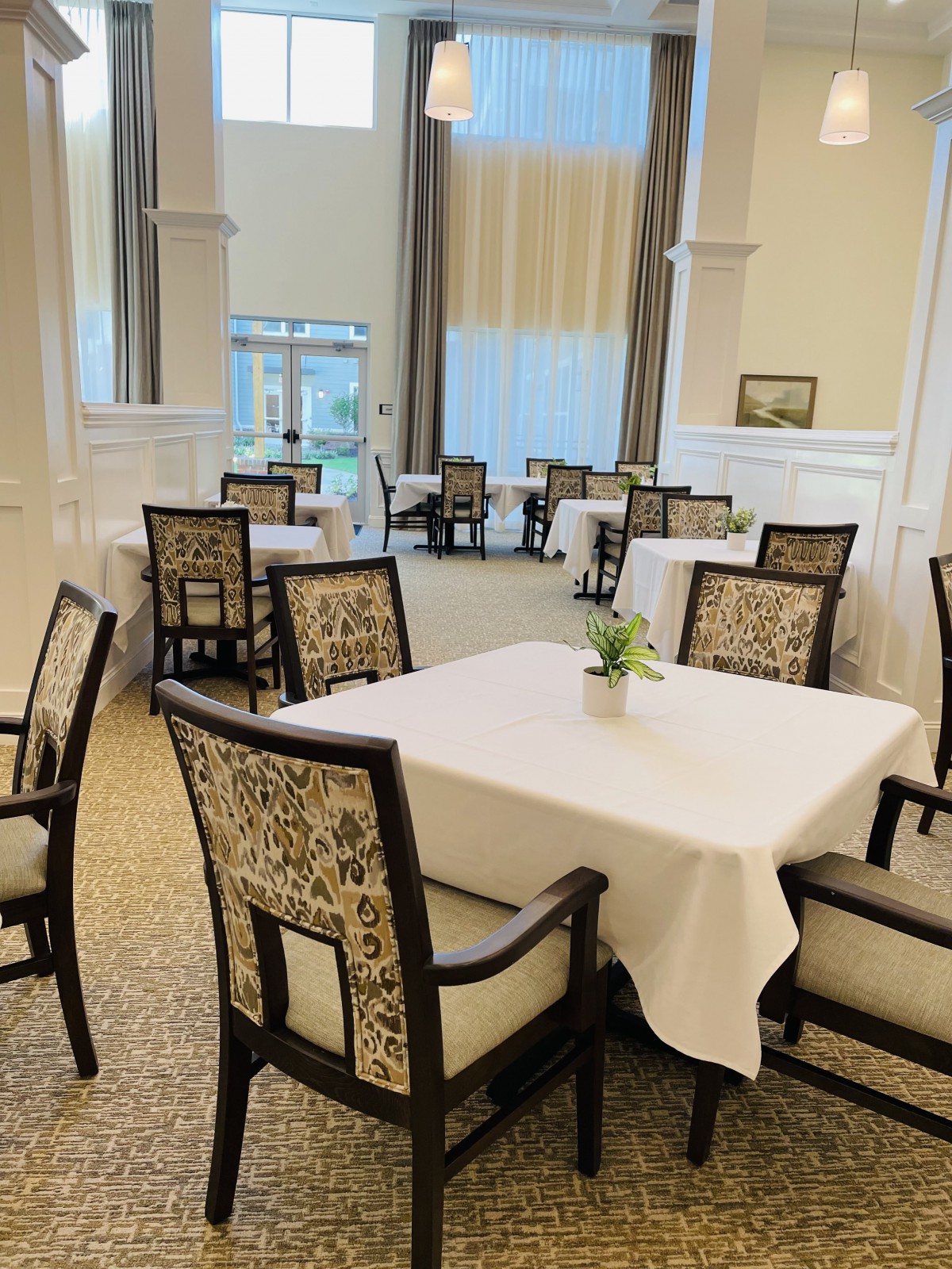 A well-arranged dining room with tables covered in white tablecloths and elegant chairs.