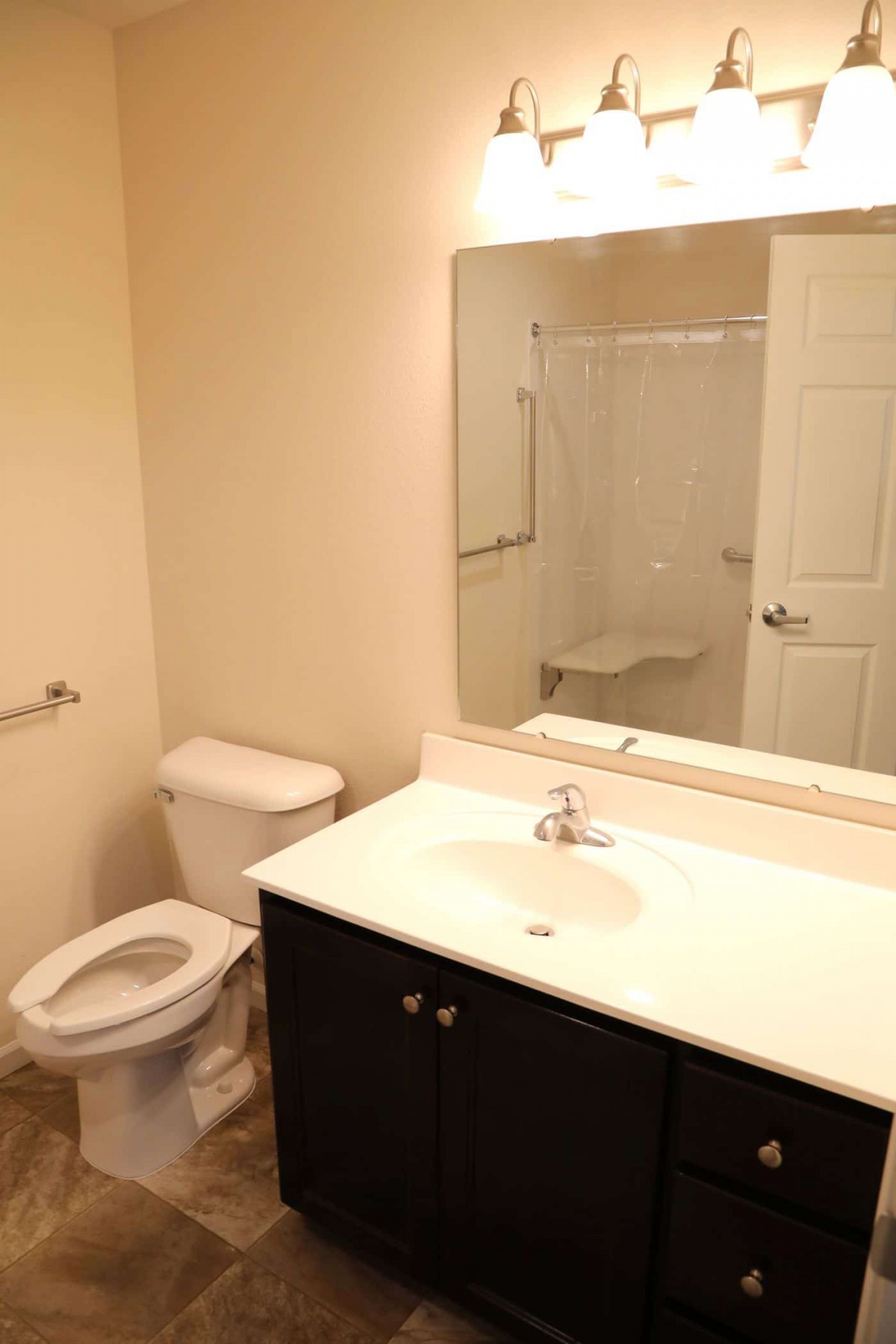 A clean and simple bathroom with a toilet, sink, mirror, and shower.