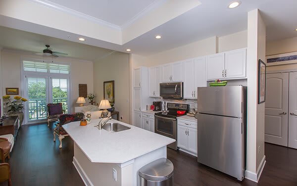 A modern kitchen featuring stainless steel appliances and white cabinetry, complete with a center island and recessed lighting.