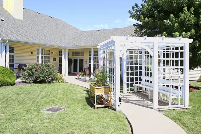A charming house with a well-maintained lawn and a pergola.