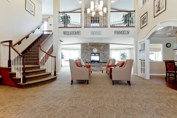 A spacious lobby with comfortable seating, a chandelier, and a staircase.