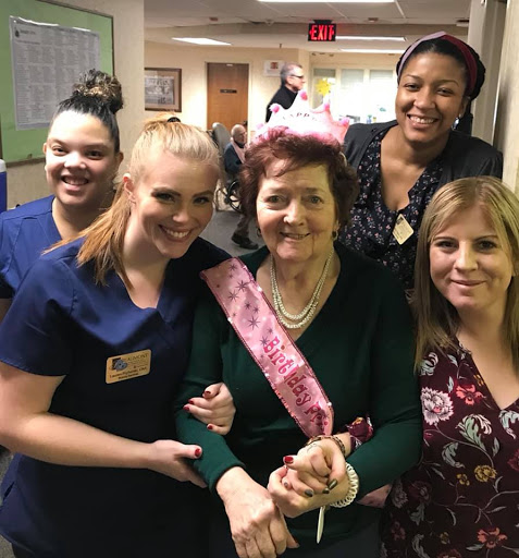 A joyful birthday celebration with a resident and her caring nursing staff.