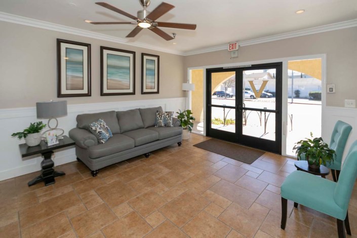 A modern living room with a comfortable sofa, artwork on the wall, and a ceiling fan providing a cozy atmosphere.