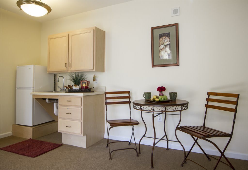 A cozy kitchen corner with a small table and chairs, decorated with flowers.
