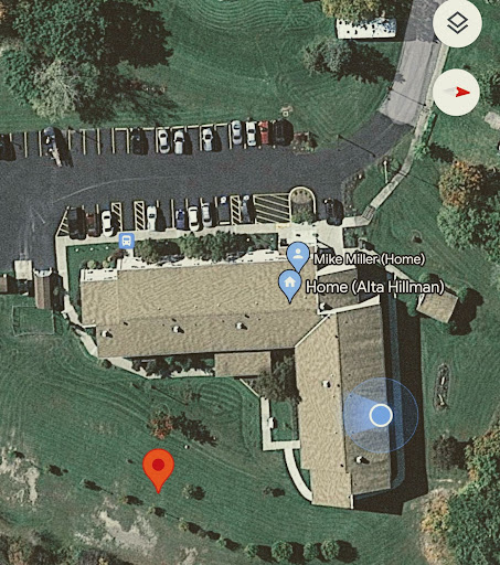 Aerial view of a property showing the layout of buildings and parking area.