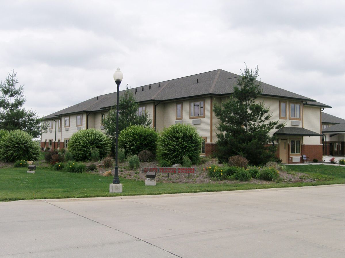 A suburban residential building surrounded by greenery under a cloudy sky.