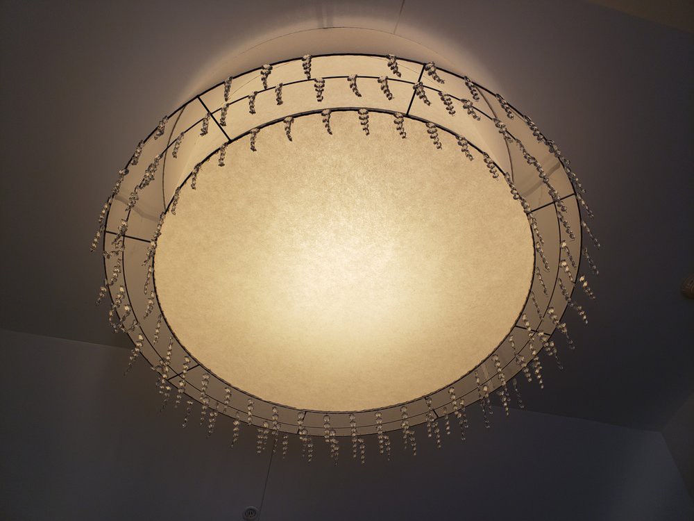 A decorative chandelier with a circular design, featuring intricate metalwork and soft ambient lighting.