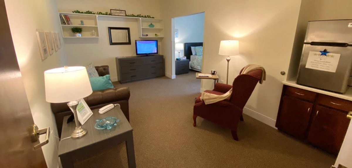 A cozy living room with an armchair, sofa, and a television.