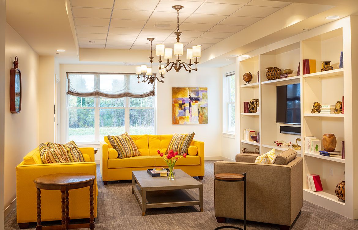 A modern living room featuring bright yellow sofas and a stylish chandelier, creating a cozy and inviting atmosphere.