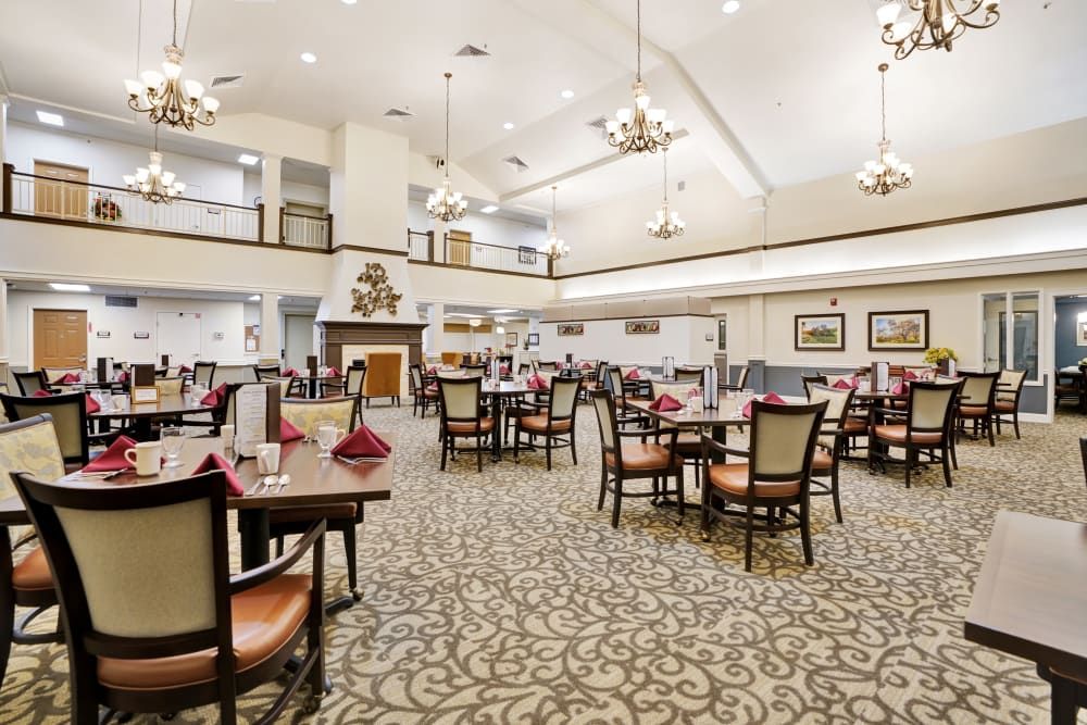 A spacious and elegantly decorated dining room with set tables and chandeliers.