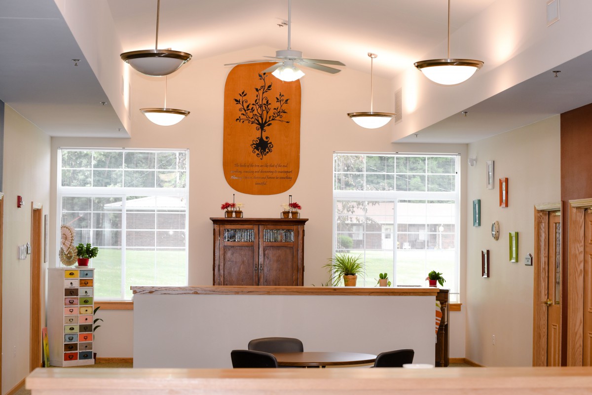 A cozy dining area with wooden furniture and pendant lighting, featuring large windows and minimalistic decor.