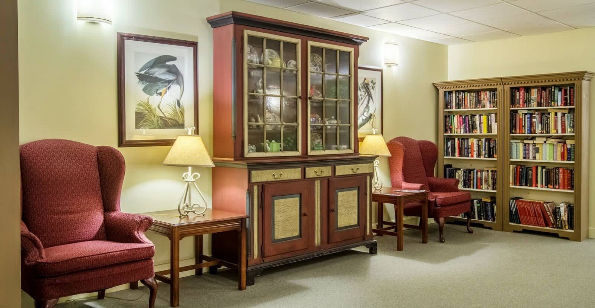 A cozy living room setup featuring a large wooden cabinet, two red armchairs, and elegant table lamps.