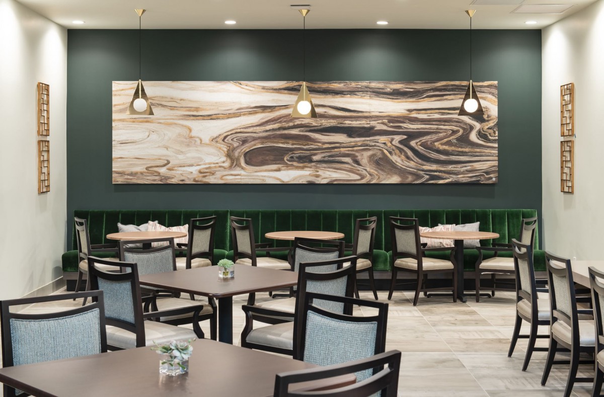 Modern restaurant dining area with abstract artwork and pendant lighting.