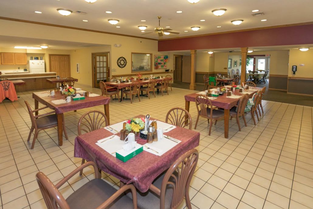 An empty dining room with tables and chairs arranged neatly, ready for guests.