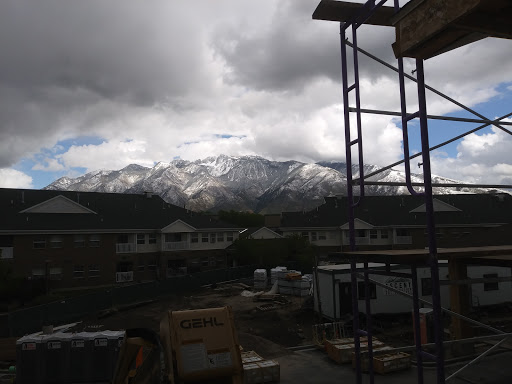 A view of snow-capped mountains under a cloudy sky, framed by construction scaffolding.