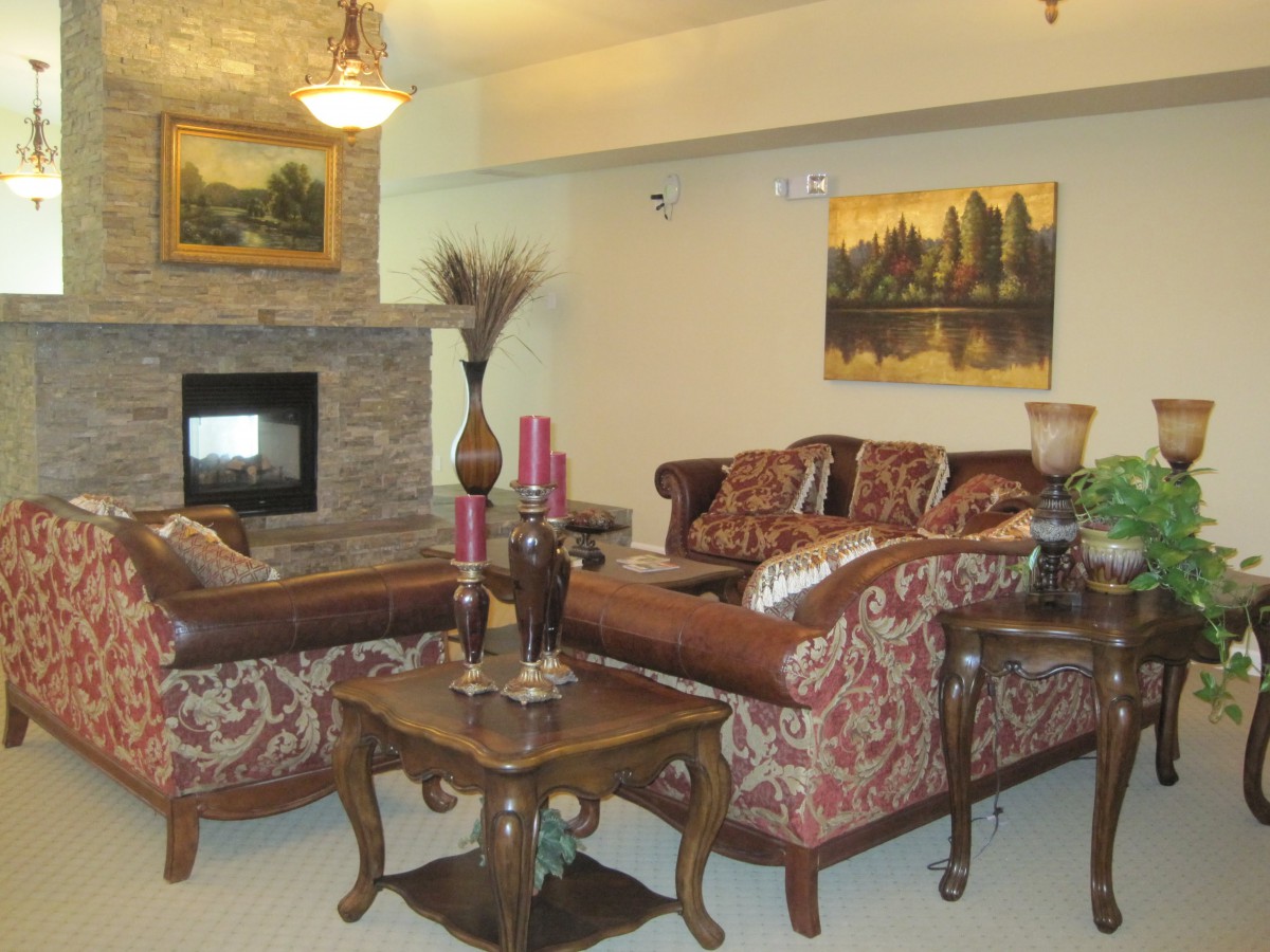 A cozy living room with ornate sofas, a stone fireplace, and elegant decor.