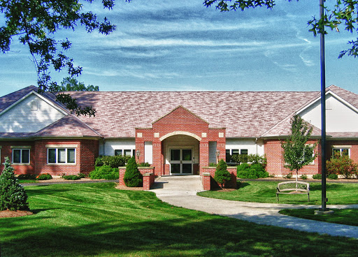 A charming brick building surrounded by well-maintained greenery and a clear blue sky.