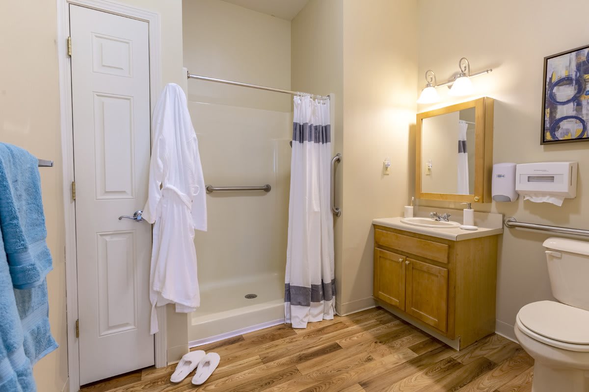 A clean and organized bathroom with a shower, vanity, and robe.