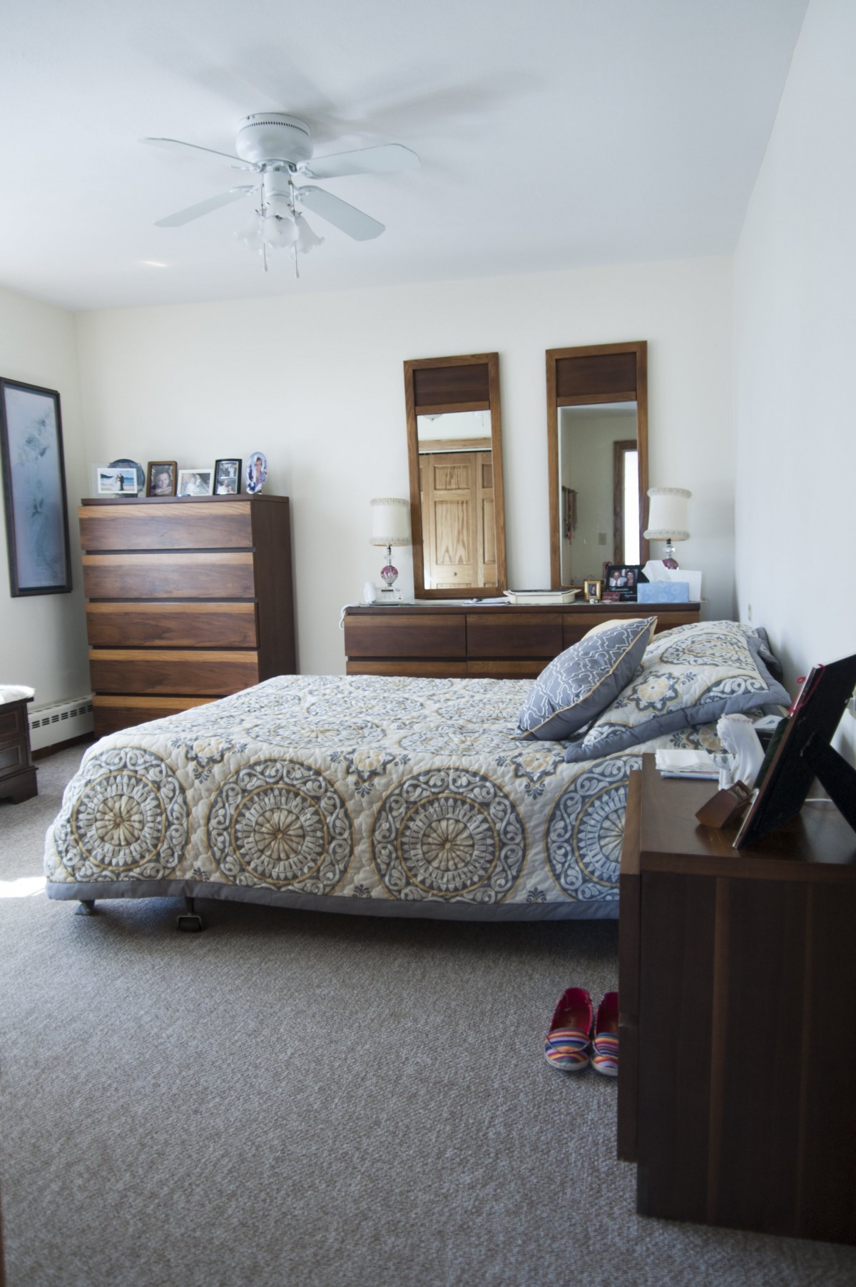 A cozy bedroom with a neatly made bed, dresser, and decorative mirrors.