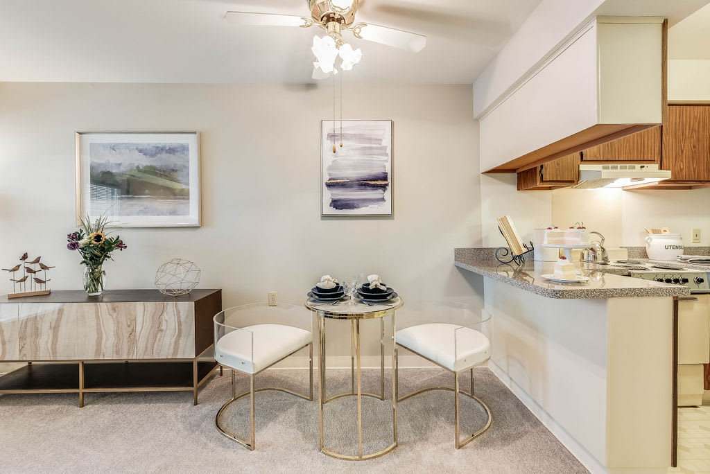 A modern dining space with a glass table and minimalist decor adjacent to a kitchen counter.