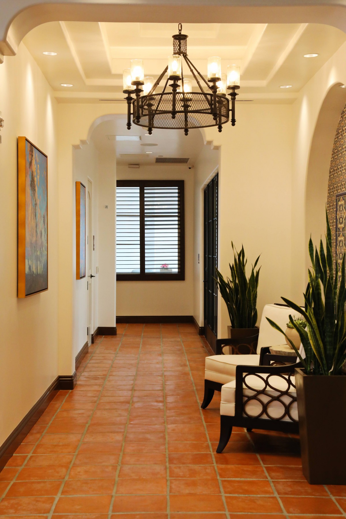 A beautifully designed hallway featuring comfortable seating, decorative plants, and elegant lighting.