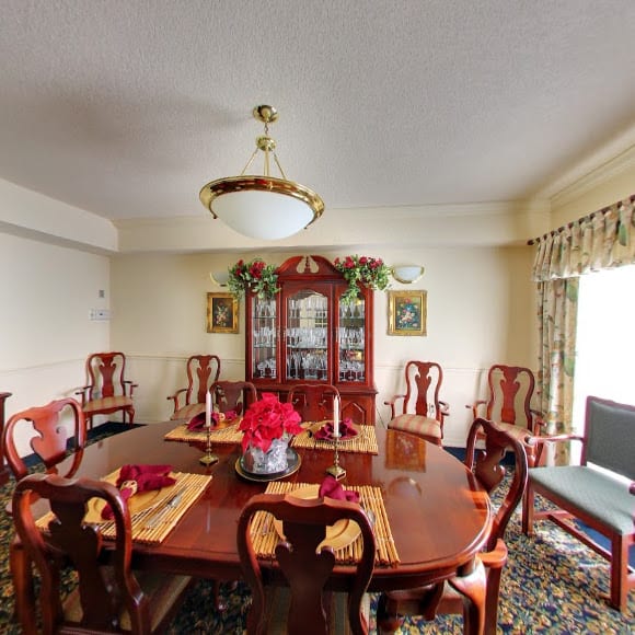 A traditional dining room with a wooden table and chairs, adorned with a chandelier and decorative elements.