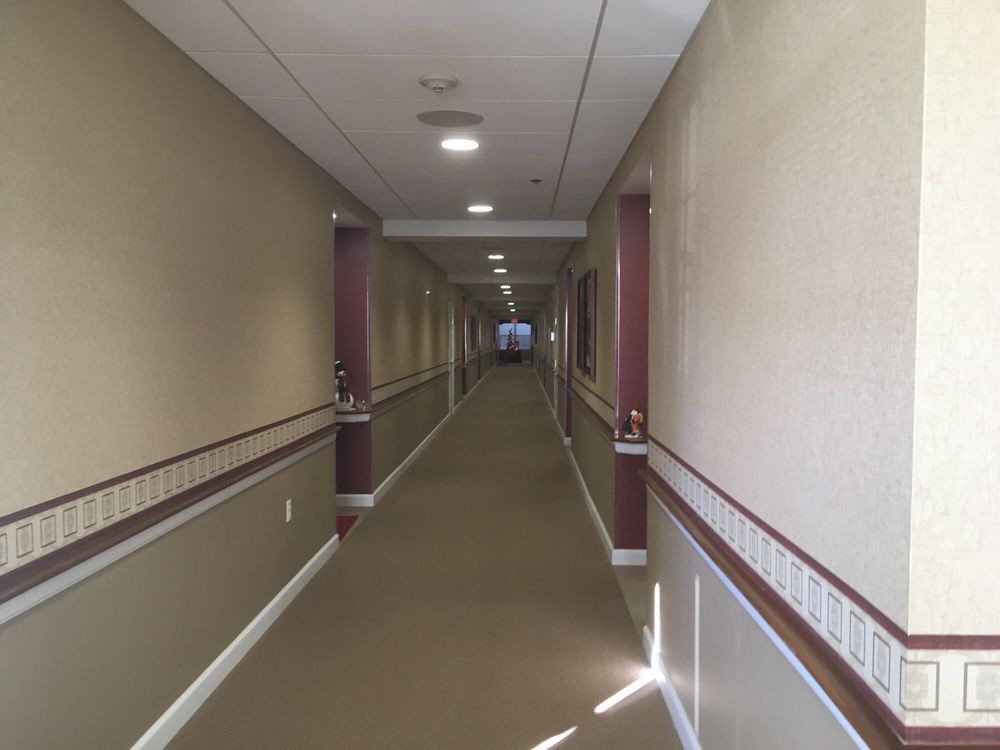 A long, carpeted hallway with ceiling lights and a distant exit.