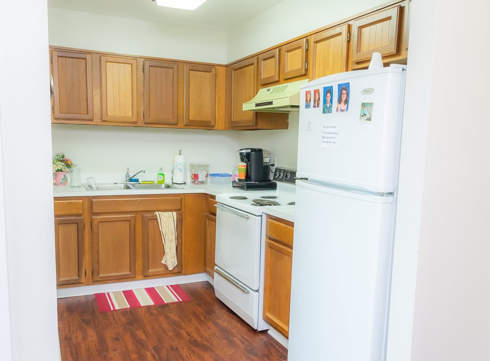 A small kitchen with wooden cabinets, a refrigerator, and an oven.