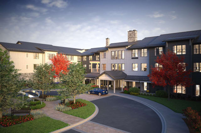 A residential building with a circular driveway and landscaped surroundings.