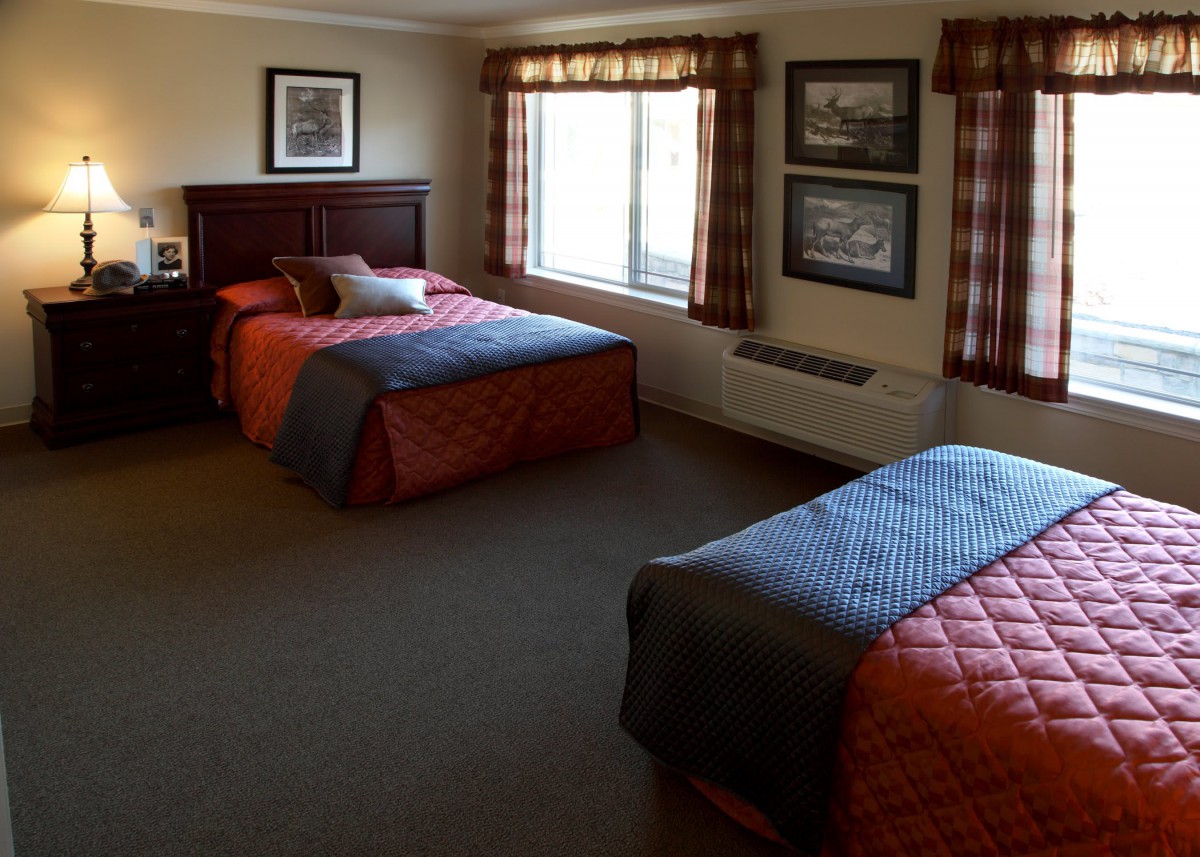 A cozy hotel room with twin beds and a window letting in natural light.