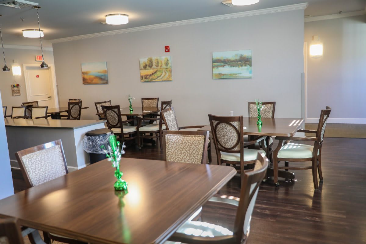 A cozy dining area with wooden tables, chairs, and wall art.