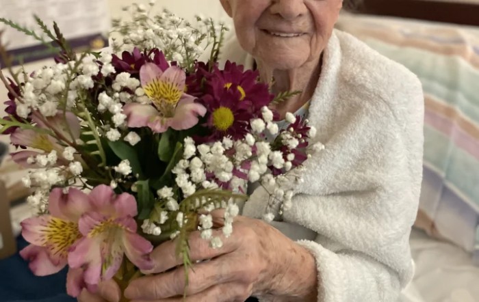 An elderly person holding a colorful bouquet of flowers.