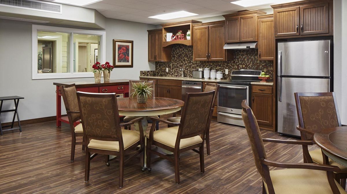 A cozy kitchen and dining area featuring wooden cabinets, a round table with chairs, and modern appliances.