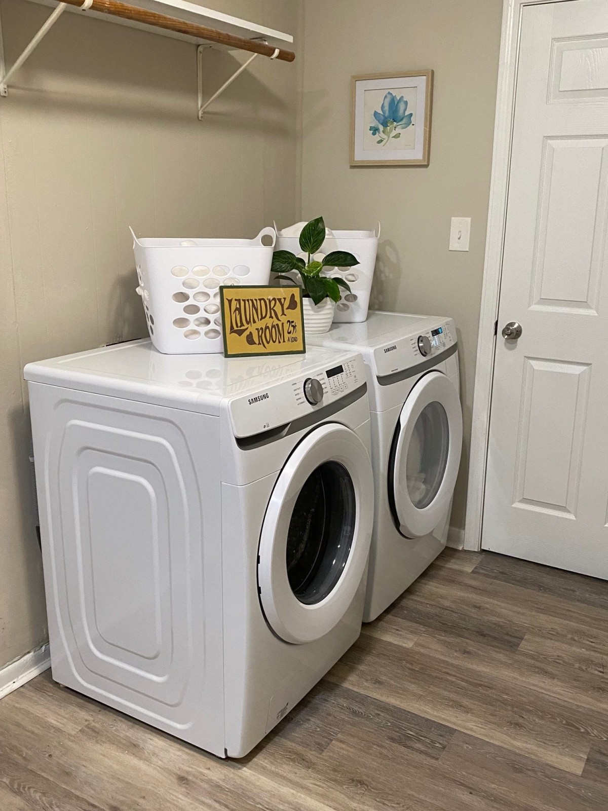 A tidy laundry room with a washing machine and dryer, decorated with a plant and a laundry basket.