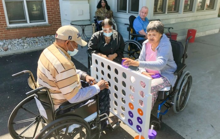 A group of elderly individuals in wheelchairs enjoy an outdoor game together.