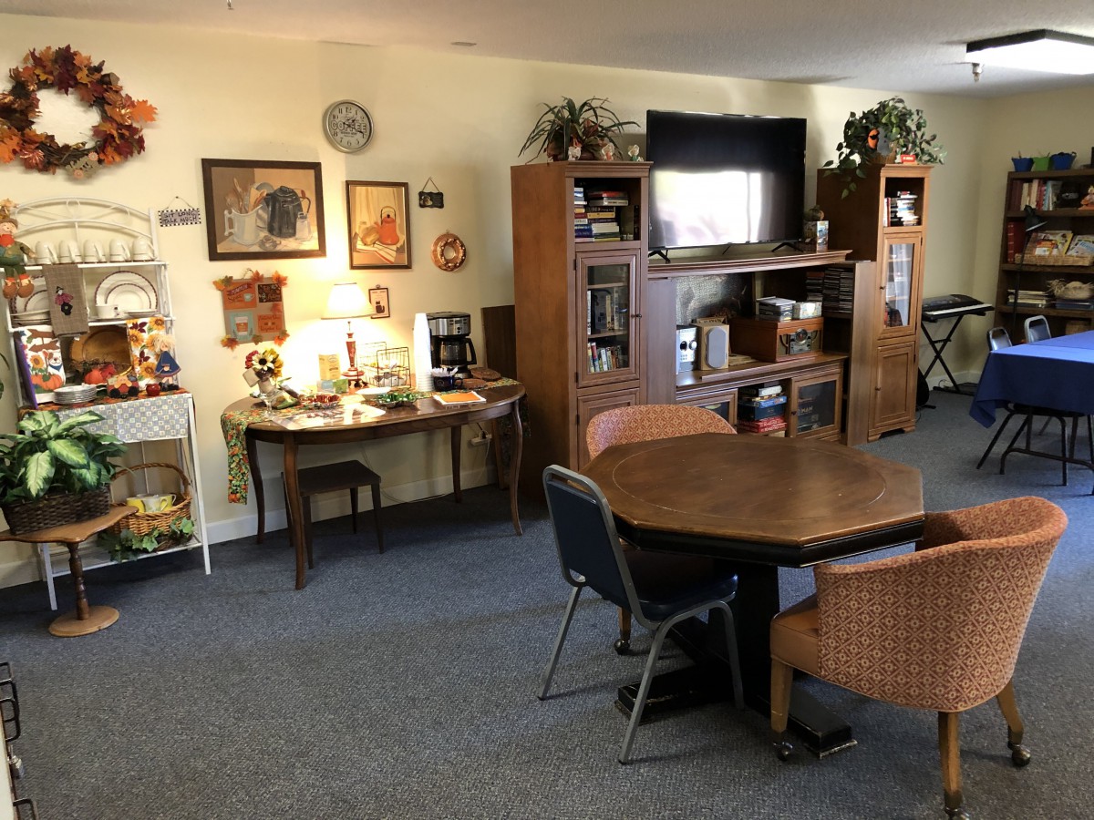 A cozy living room with a table and chairs, an entertainment center with a television, and various decorations.