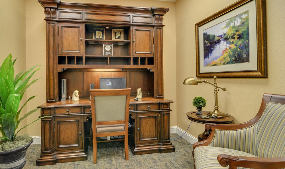 A traditional office setup featuring a wooden desk with a chair and bookshelf.